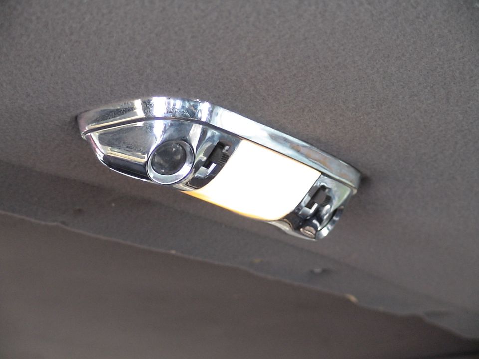 Chrome interior dome light with a clear lens and a white light cover, mounted on a grey headliner