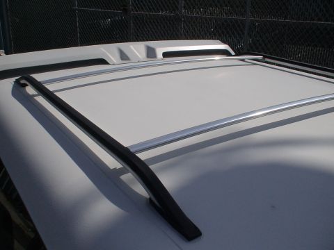 1993 Ford C-350 (Centurion Conversions) - Close-up view of a white vehicle's roof, showing the installed roof rack system with crossbars and side rails.