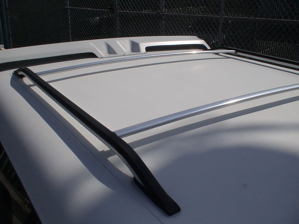 White vehicle roof with black and aluminum roof rack side rails and fiberglass sun visor
