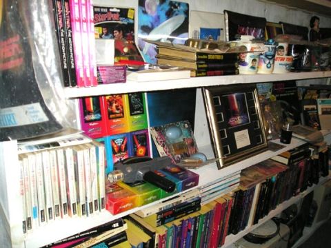 1984 Pontiac Fiero - A collection of Star Trek merchandise is displayed on multiple shelves, including books, DVDs, and decorative items.