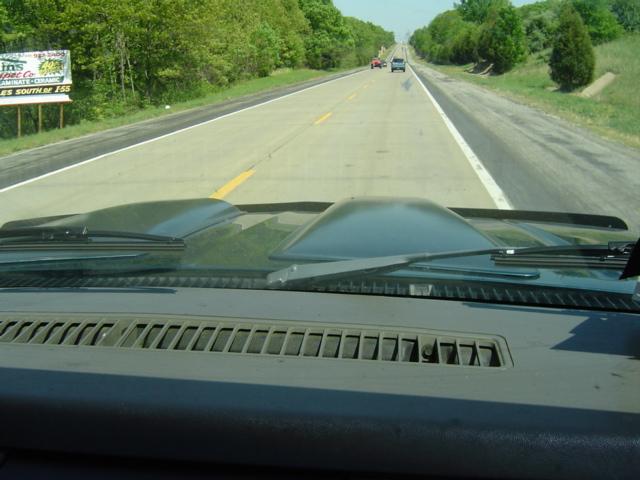 Green dashboard and hood with dual scoops, seen from inside a vehicle driving on a highway