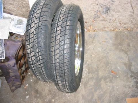 1985 Ford LTD Crown Victoria - A close-up view of two tires and a car engine part on a concrete surface.