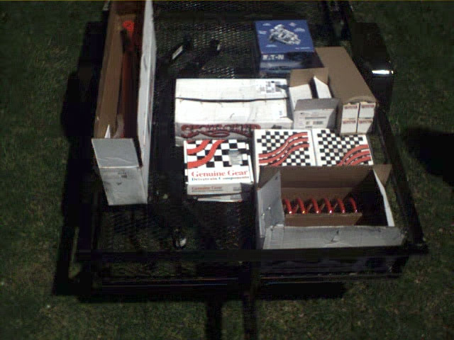 Trailer loaded with boxes of vehicle parts, including springs and gears