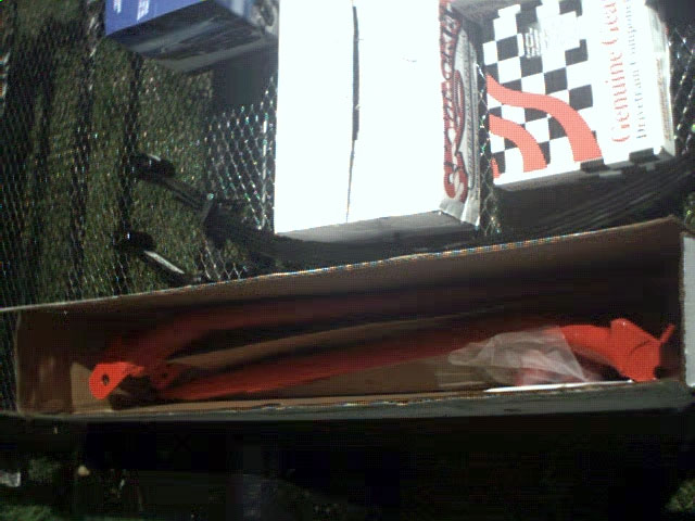 Orange suspension parts in a cardboard box with "Genuine Gear" packaging in the background