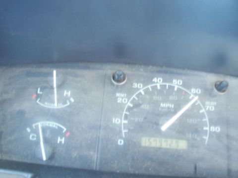 1994 Ford F-150 - Dusty Ford truck instrument cluster photographed while moving, with the speedometer needle just past 60 MPH and the mechanical odometer rea…
