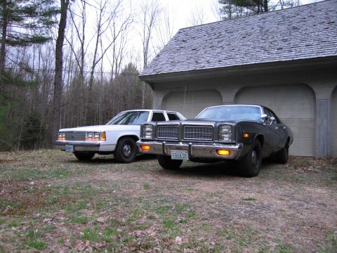 1991 Ford LTD Crown Victoria - Two older model sedans are parked outside a garage on a cloudy day.