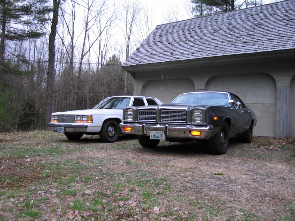 white sedan and a dark sedan parked in front of a garage