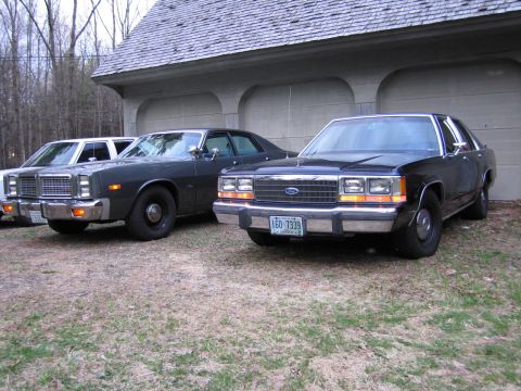 1991 Ford LTD Crown Victoria - Three sedans, including a 1991 Ford Crown Victoria LTD, are parked in front of a garage.
