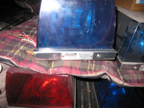 1991 Ford LTD Crown Victoria - blue Federal emergency beacon and a red beacon rest on a plaid blanket, with another blue light visible to the right.