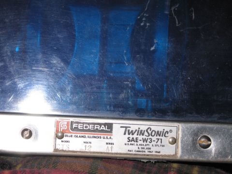 1991 Ford LTD Crown Victoria - Close-up of a Federal Twin Sonic SAE-W3-71 nameplate, Blue Island Illinois, mounted on the chrome base of a blue beacon.