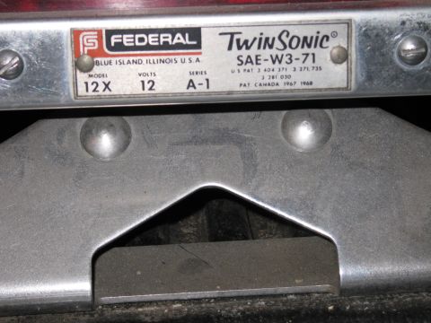 1991 Ford LTD Crown Victoria - Federal Twin Sonic model 12X SAE-W3-71 nameplate sits above a gray metal mounting bracket for the beacon.