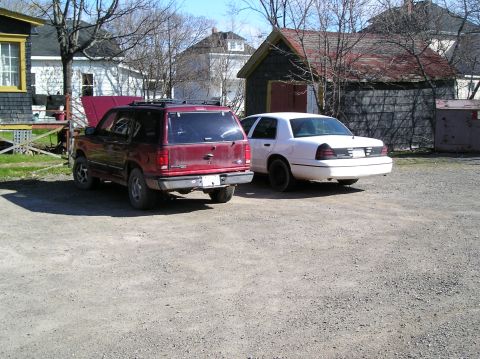 1991 Ford Explorer - A red 1991 Ford Explorer with its hood open is parked next to a white sedan in a gravel lot.