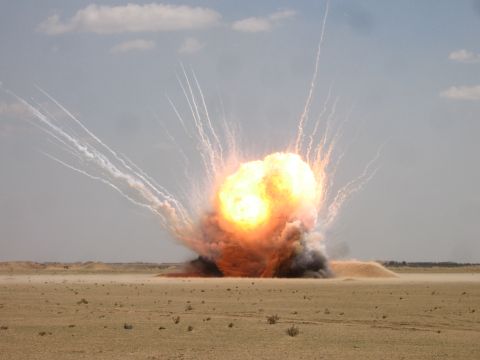 1979 Ford Bronco - A massive explosion erupts in a barren desert under a hazy sky.