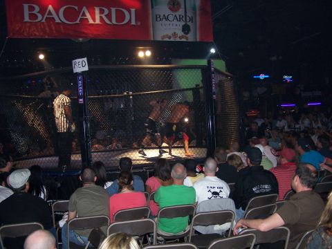 1979 Ford F-150 - An MMA fight takes place in a cage as a crowd watches, with a Bacardi banner visible above.
