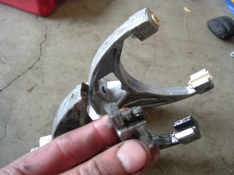 1989 Ford Bronco - A damaged transfer case shift fork is shown, with a broken piece detached and held by a hand.