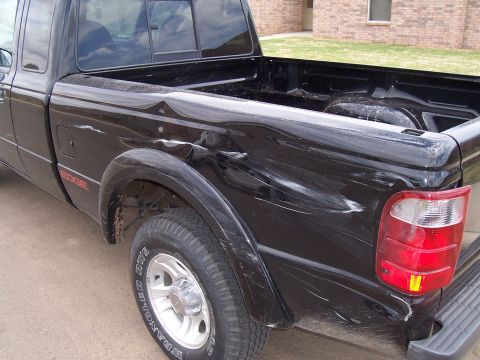 2003 Ford Ranger - This black Ford Ranger pickup truck shows extensive damage to its side and rear, indicating it has been in a wreck.