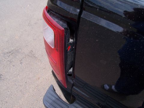 2003 Ford Ranger - Close-up of a damaged black pickup truck taillight assembly, revealing broken plastic and exposed components.
