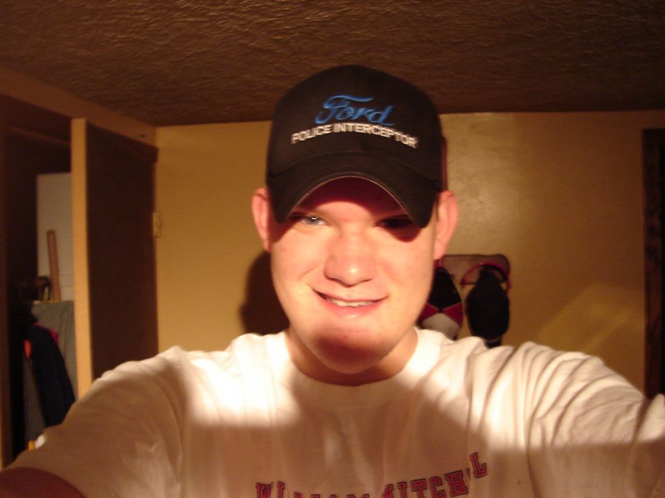 Man wearing a black Ford Police Interceptor baseball cap and a white t-shirt