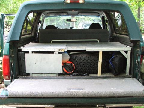 1996 Ford Bronco - Rear storage area of a 1996 Ford Bronco, equipped with a spare tire and camping gear.