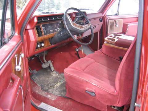 1984 Ford F-150 - Interior view of a red 1984 Ford F-150, wood-grain trim on the dashboard and plush red carpeting.