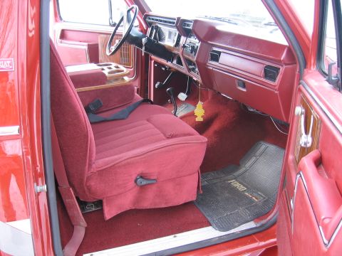 1984 Ford F-150 - The interior of a red Ford truck, a plush seat and dashboard details.
