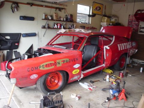 1968 Ford Torino - A red 1968 Ford Torino race car is undergoing modifications in a cluttered garage.