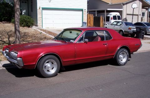 1972 Ford Ranchero - A red coupe with a vinyl top is parked on a street in front of a house.