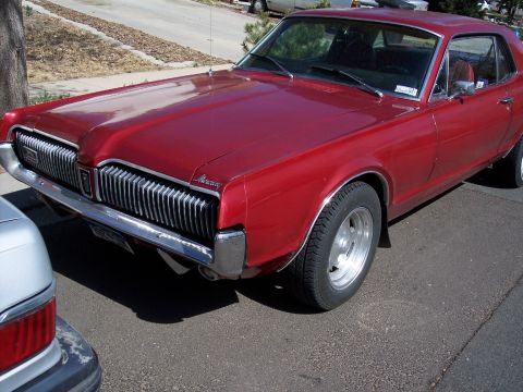 1972 Ford Ranchero - A red Mercury Cougar is parked on a street, showing its distinctive grille and front end.