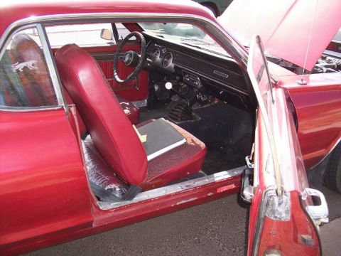 1972 Ford Ranchero - The interior of a red 1967 Mercury Cougar shows its red seats, dashboard, and manual transmission shifter.