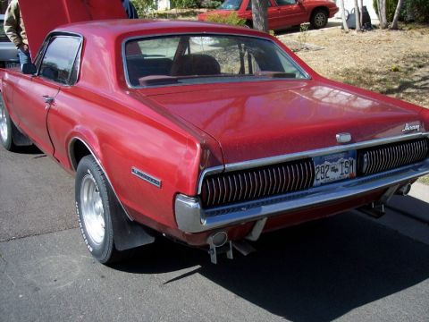 1972 Ford Ranchero - This red coupe features a distinctive chrome grille and dual exhaust pipes, viewed from its rear end.