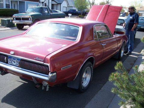 1972 Ford Ranchero - A red 1969 Mercury Cougar XR7 is parked with its hood open, showing a green pickup truck in the background.