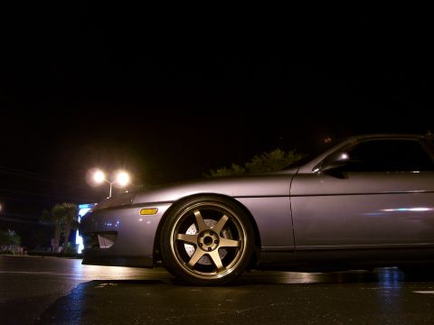 1994 Ford Probe - Side view of a silver coupe with aftermarket wheels under streetlights at night.