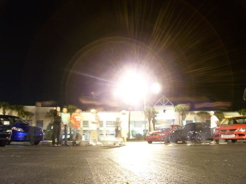 1994 Ford Probe - Cars and people gathered at night under intense lighting.
