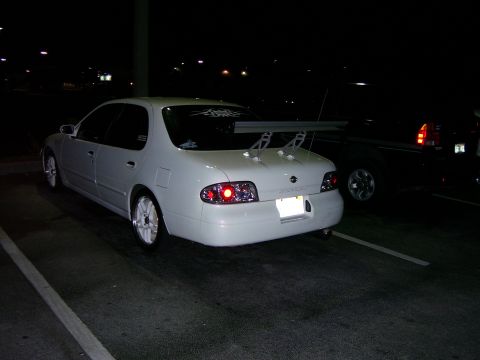 1994 Ford Probe - A white sedan with a large rear spoiler and aftermarket wheels is parked in a lot at night.