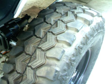 1989 Ford Bronco - Detail shot of a off-road tire and visible suspension components, suggesting off-road capability.