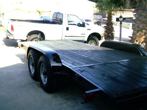 1989 Ford Bronco - A white pickup truck is parked beside a black trailer, likely for transport.