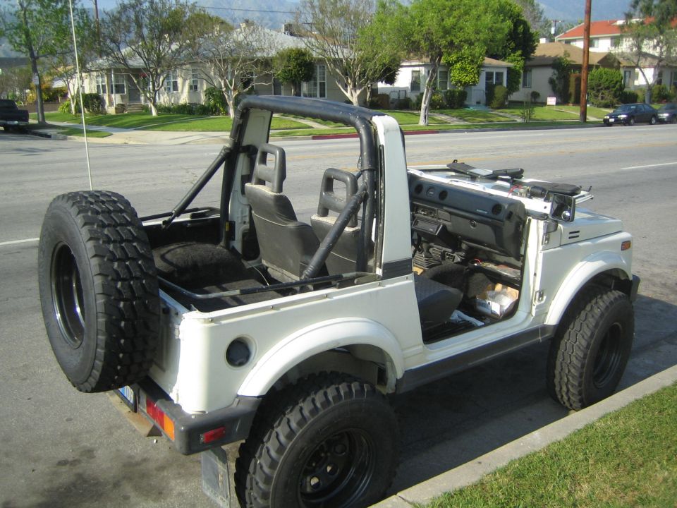 White Suzuki Samurai 4x4 with top removed and spare tire on rear