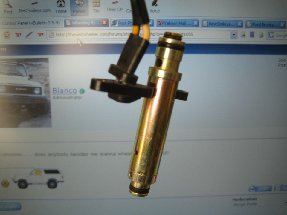 Close-up of a brass fuel injector with black plastic connector