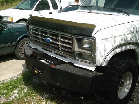 1986 Ford Bronco - Front view of a 1986 Ford Bronco, showing its winch plate bumper and grille. Other vehicles are partially visible.