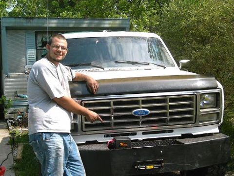 1986 Ford Bronco - A man points to the grille of a 1986 Ford Bronco, which features a winch plate bumper.