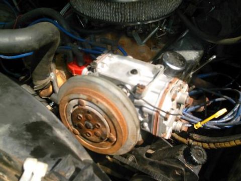 1986 Ford Bronco - Close-up view of an engine bay, focusing on the air cleaner and AC compressor assembly.