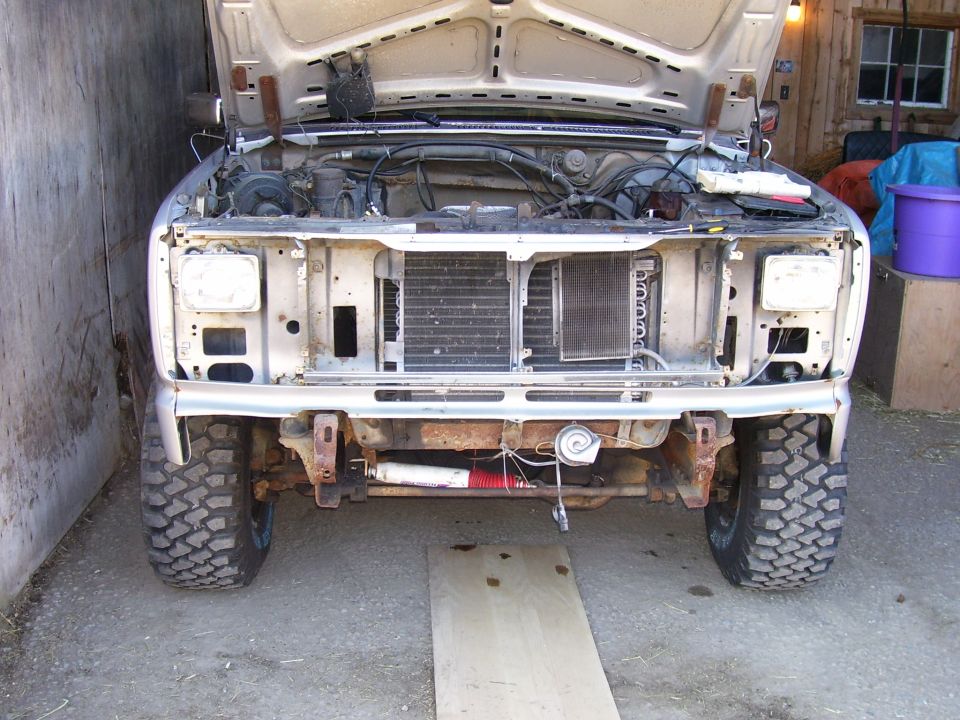 Front of a truck with hood up, grille removed, showing engine bay and radiator