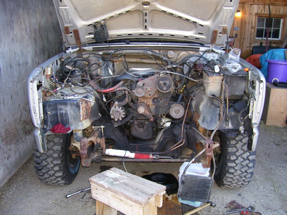 Engine bay of a truck with hood open, showing engine and front suspension