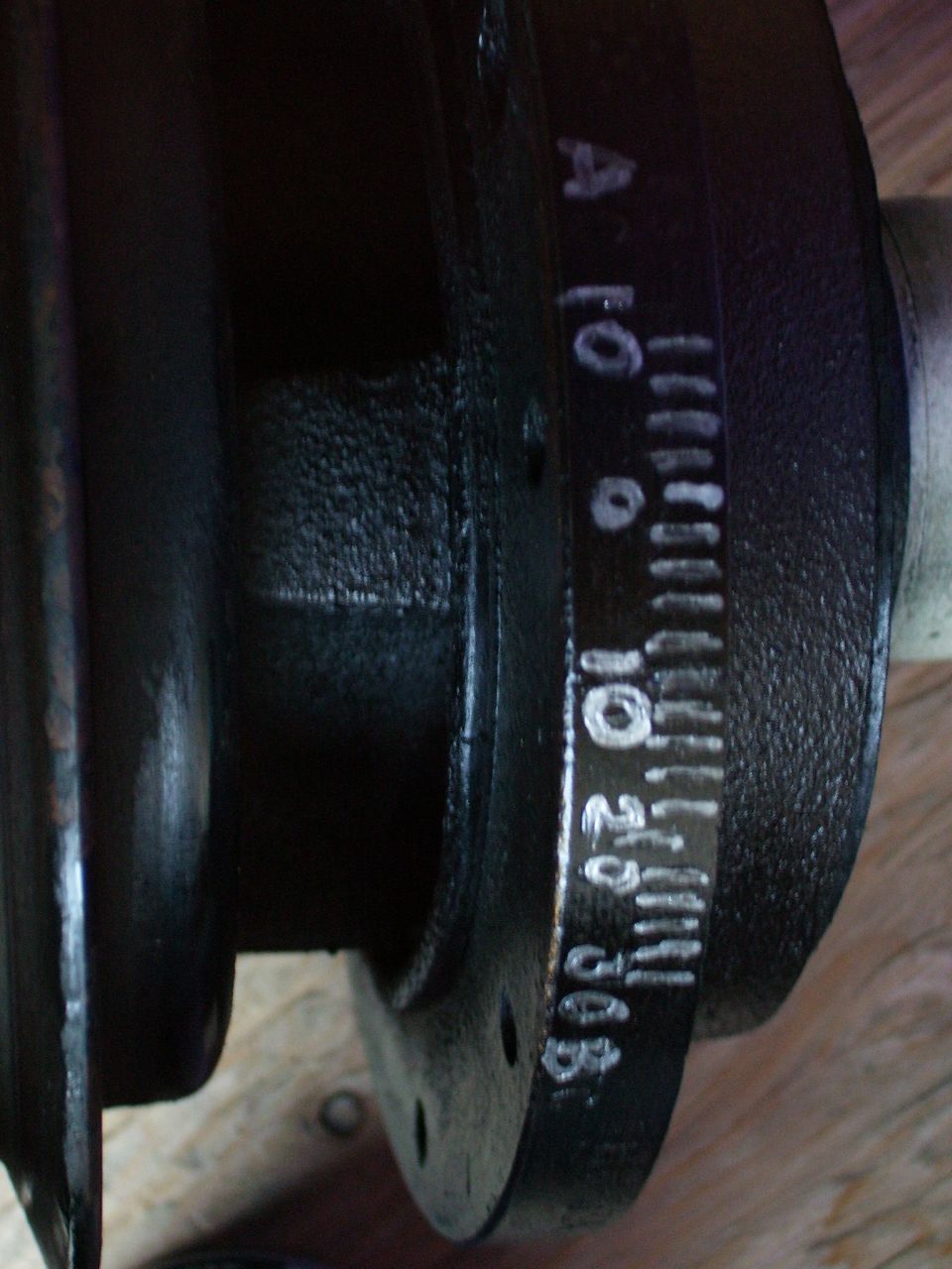 Close-up of a crankshaft with white timing marks and numbers like 0, 10, 20, 30