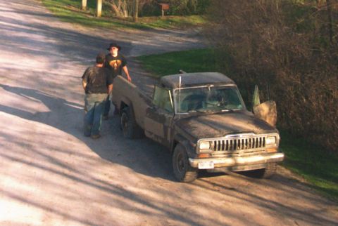 1979 Ford F-150 - A dusty Jeep Comanche pickup truck is parked on a dirt road with two people nearby.