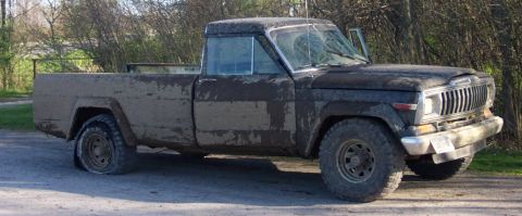 1979 Ford F-150 - This muddy Jeep J-10 pickup truck has a flat tire on the driver's side front.
