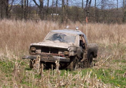 1979 Ford F-150 - This truck is covered in mud and appears to be stuck in a field with dry grass and trees in the background.