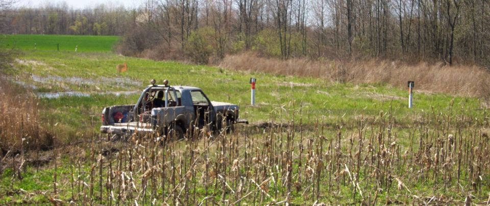 Pickup truck stuck in a muddy field with trees in the background