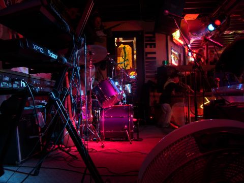 1994 Ford Probe - A dimly lit stage features a drum kit and keyboards, illuminated by colorful stage lighting.