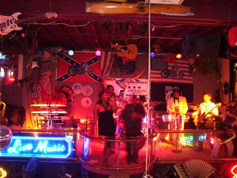1994 Ford Probe - A band performs on a stage adorned with flags and neon signs, creating a lively atmosphere for live music.